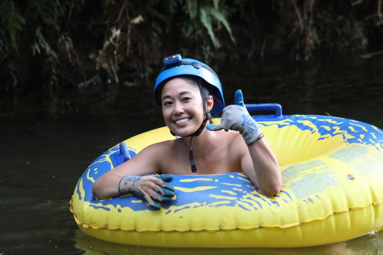 Person in a yellow-blue inflatable ring in water, wearing a helmet, smiling, and giving a thumbs up.