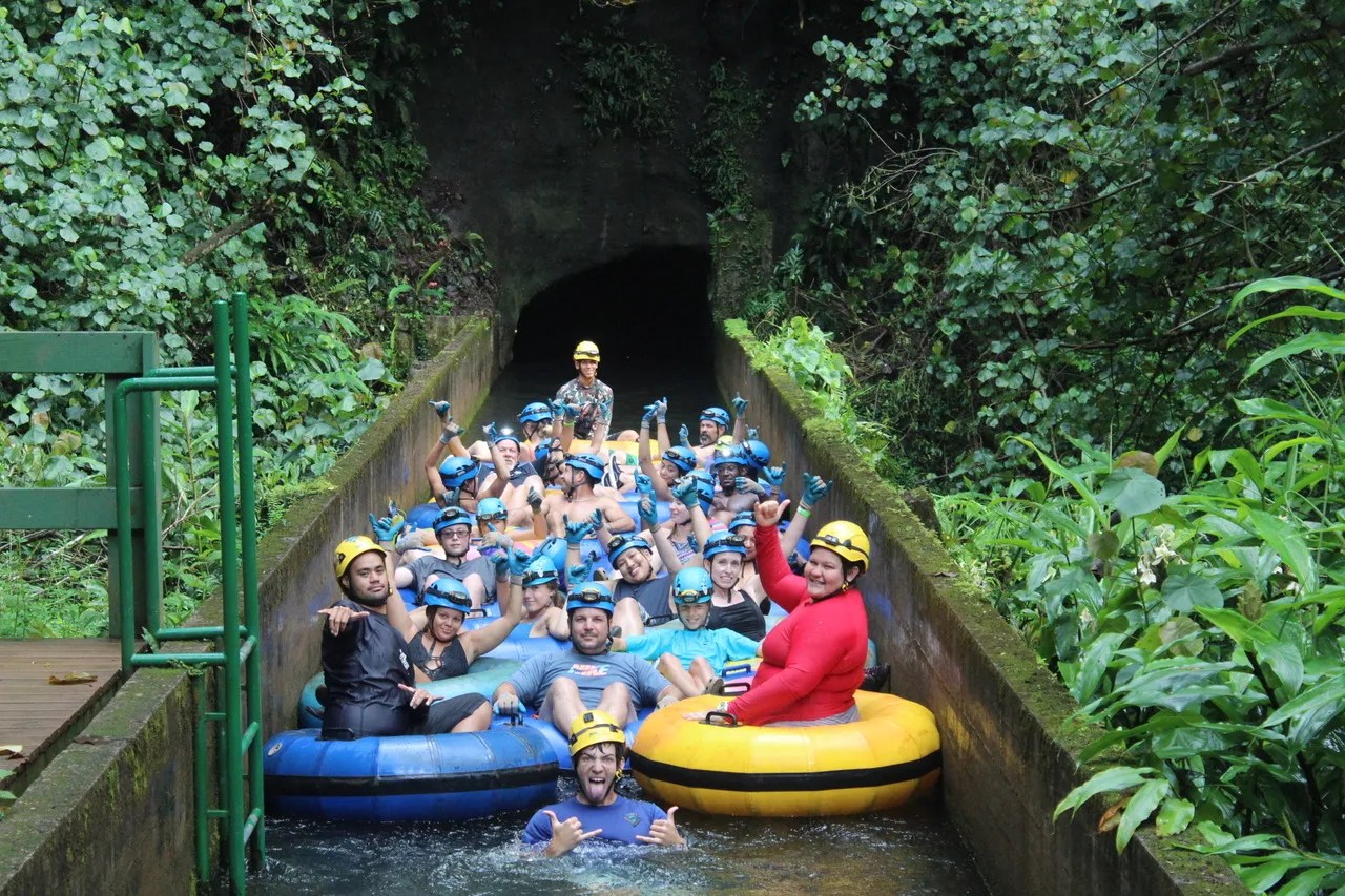 Group of people in helmets and life jackets on colorful tubes in a jungle water ride.