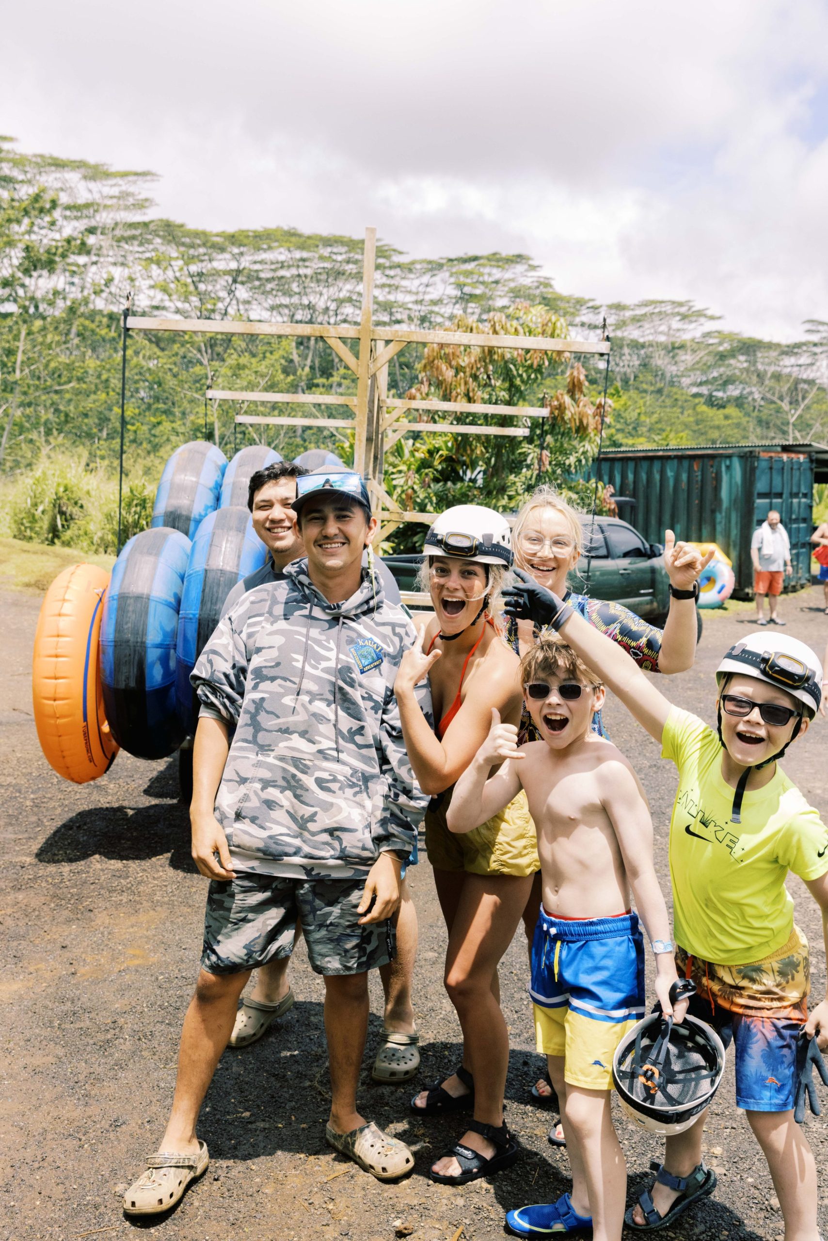 Group of people smiling in outdoor setting with inner tubes and helmets.